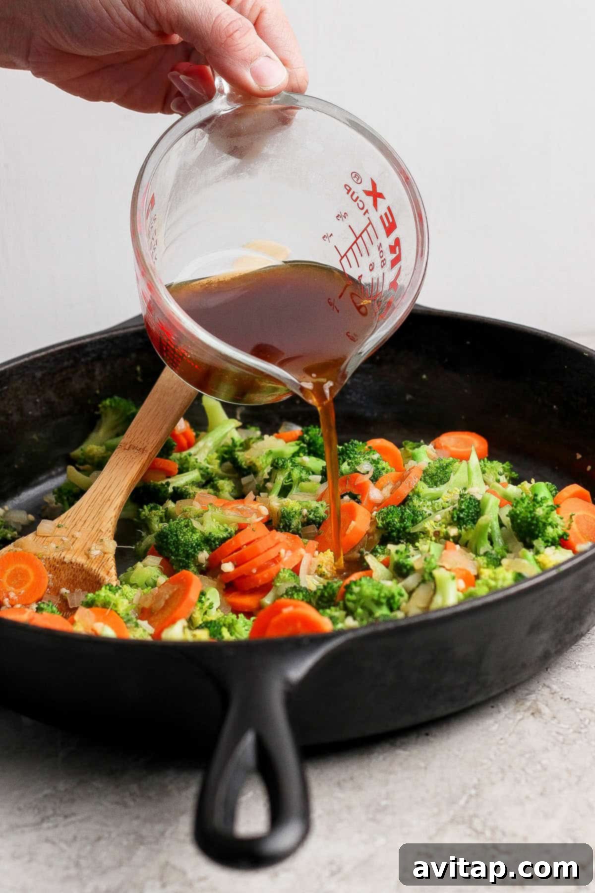Ground Beef with Broccoli Florets 3 Adding sauce to the sautéed broccoli and carrots in a cast iron skillet.