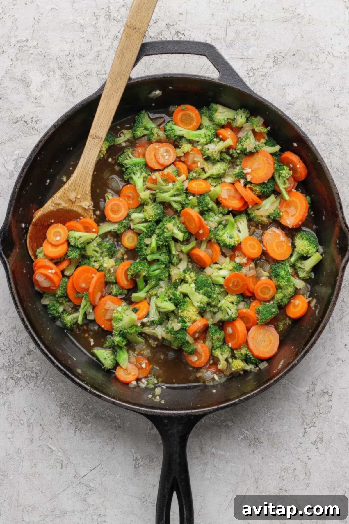 Ground Beef with Broccoli Florets 4 Sautéed broccoli and sliced carrots being stirred in a cast iron skillet.