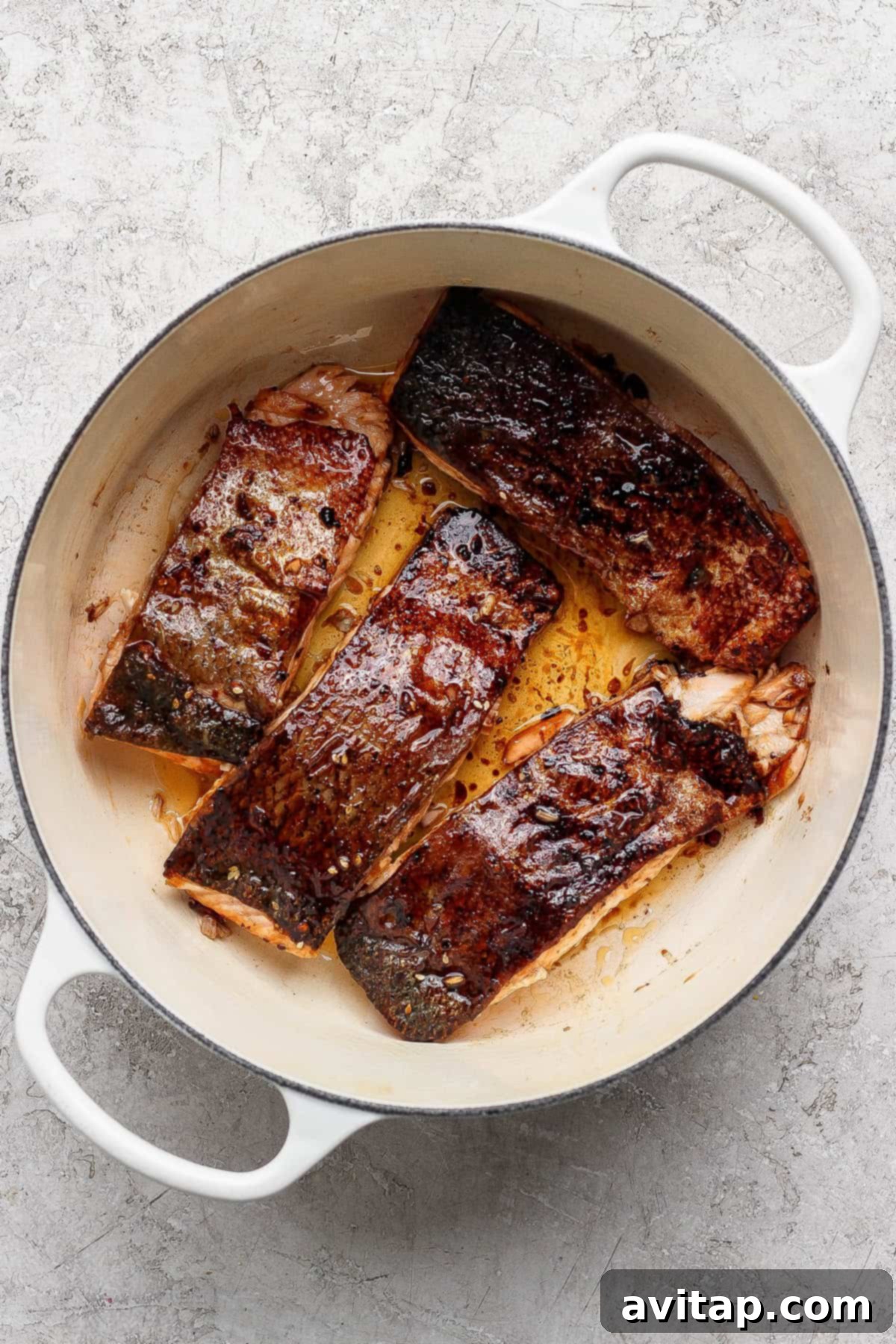 Seared salmon fillets cooking in a pan.