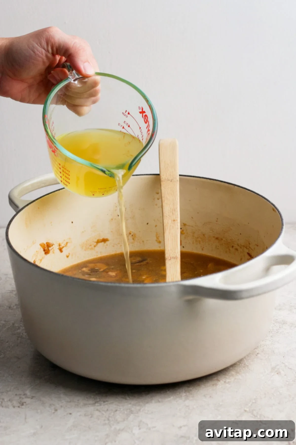 Broth being poured into a pot with other ingredients.