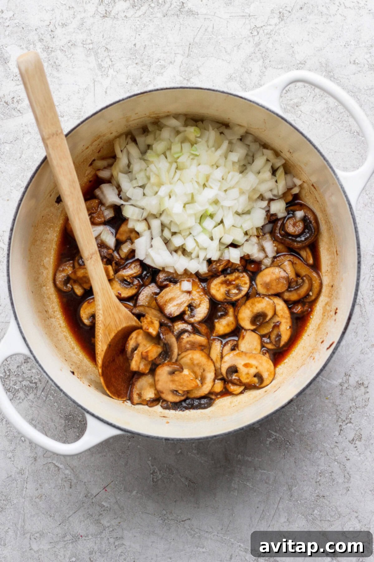 Mushrooms and onions sautéing in a pot.