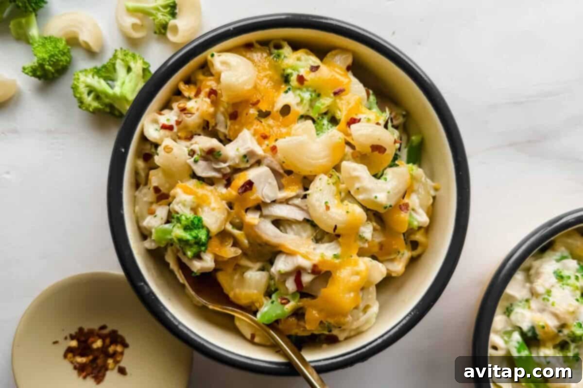 A creamy bowl of Chicken Broccoli Cottage Cheese Mac and Cheese, garnished with melted cheese and red pepper flakes.