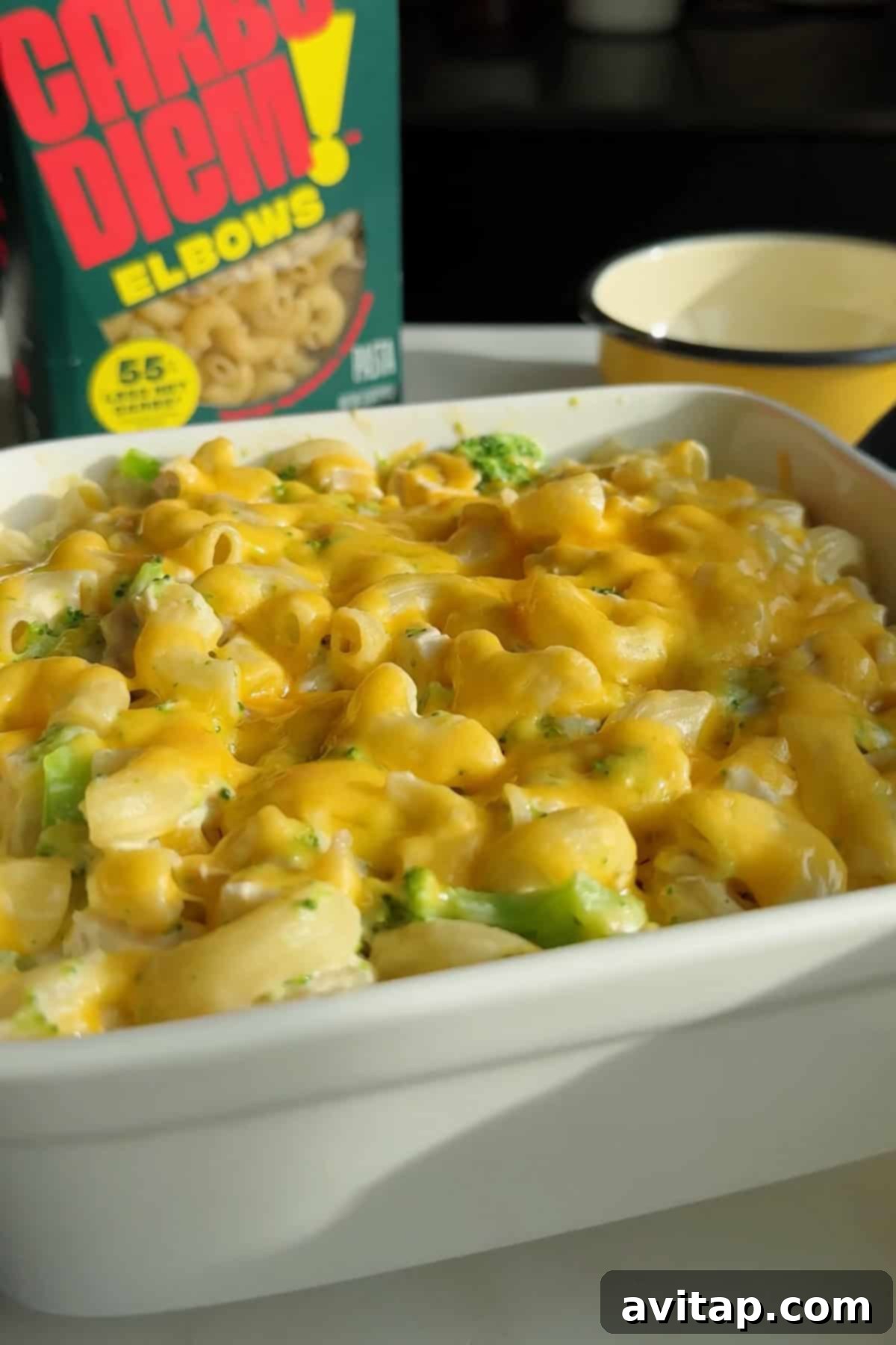 Mac and cheese in a white dish topped with melted cheese and broccoli.