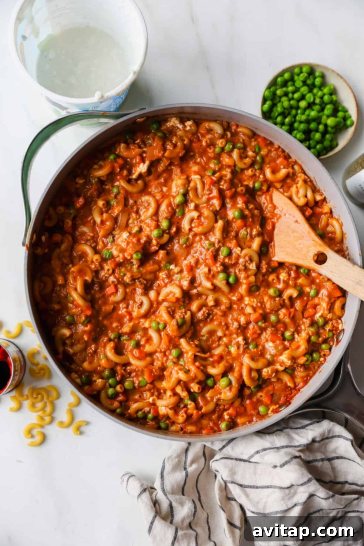 Cottage Cheese Boost: Hamburger Helper Upgrade 3 Preparing the Cottage Cheese Hamburger Helper: stirring macaroni in a pan with tomato sauce and peas.
