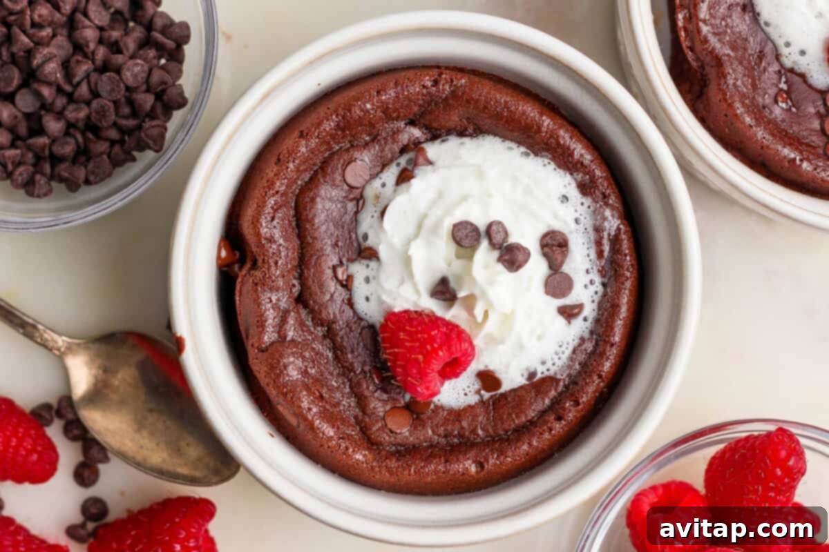 A decadent chocolate lava cake in a ramekin with whipped cream, chocolate chips, and a raspberry.