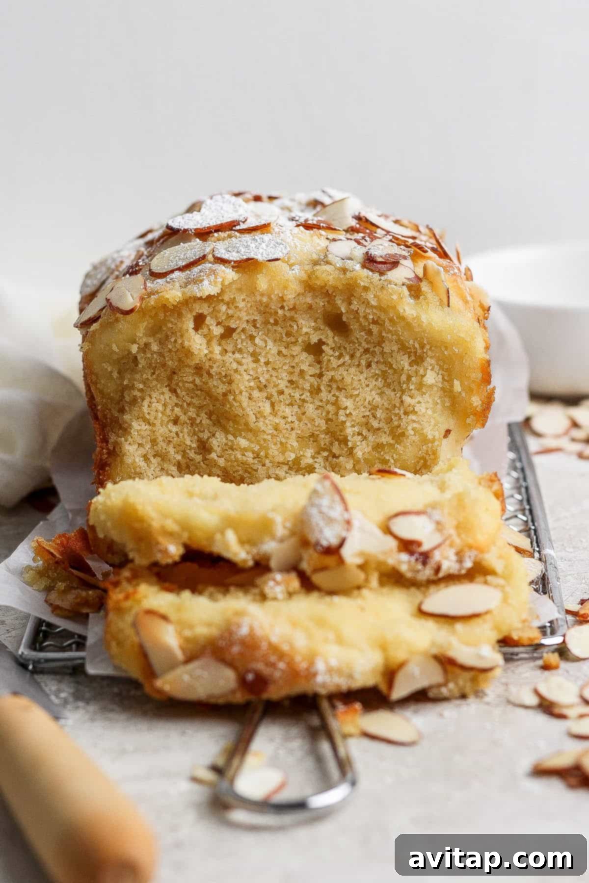 A loaf of almond croissant cottage cheese pull-apart bread, showcasing its golden crust and almond topping, with sliced portions revealing the creamy filling.
