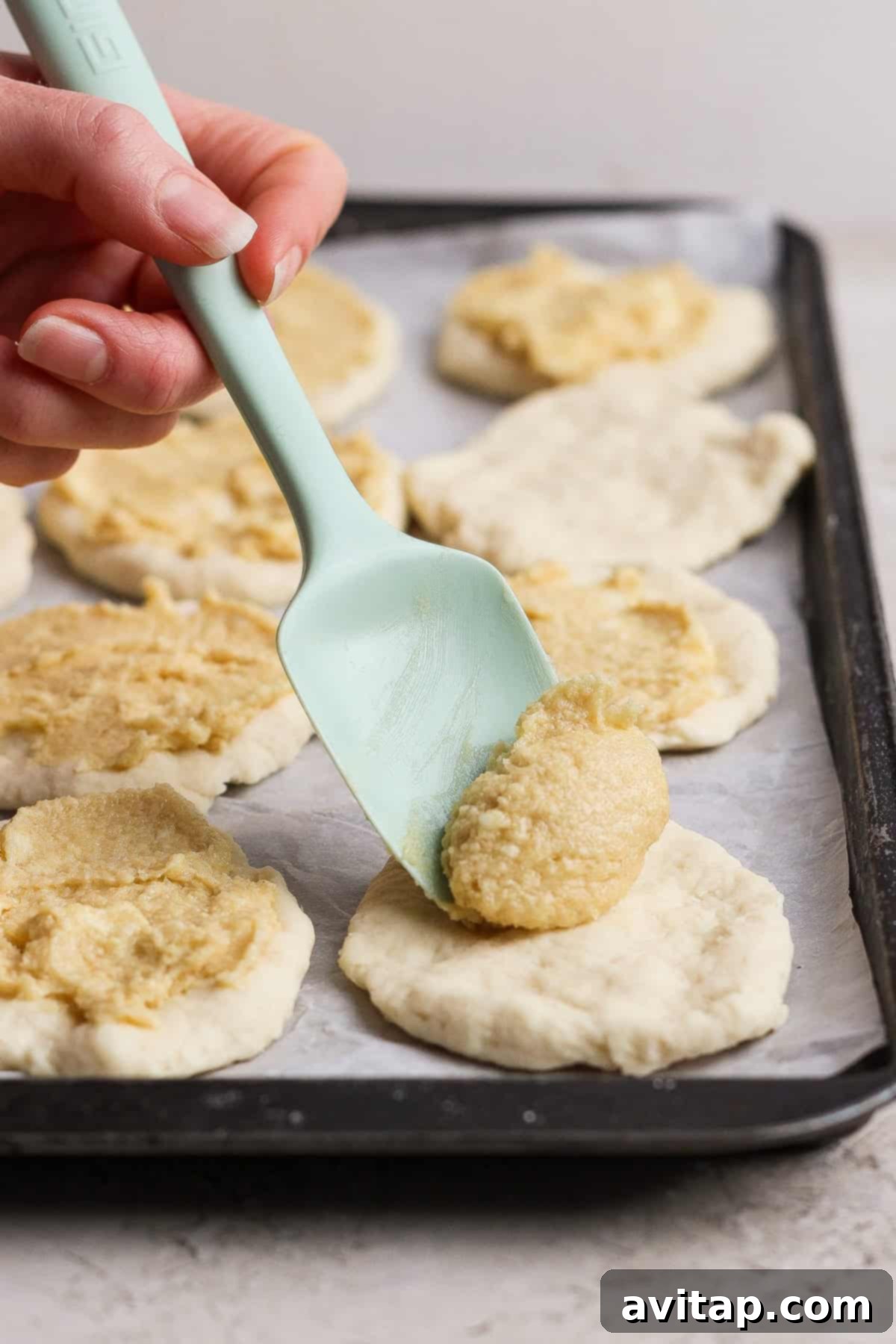 Close-up view of the cottage cheese filling being spread onto dough rounds, highlighting the texture and preparation process of the pull-apart bread.