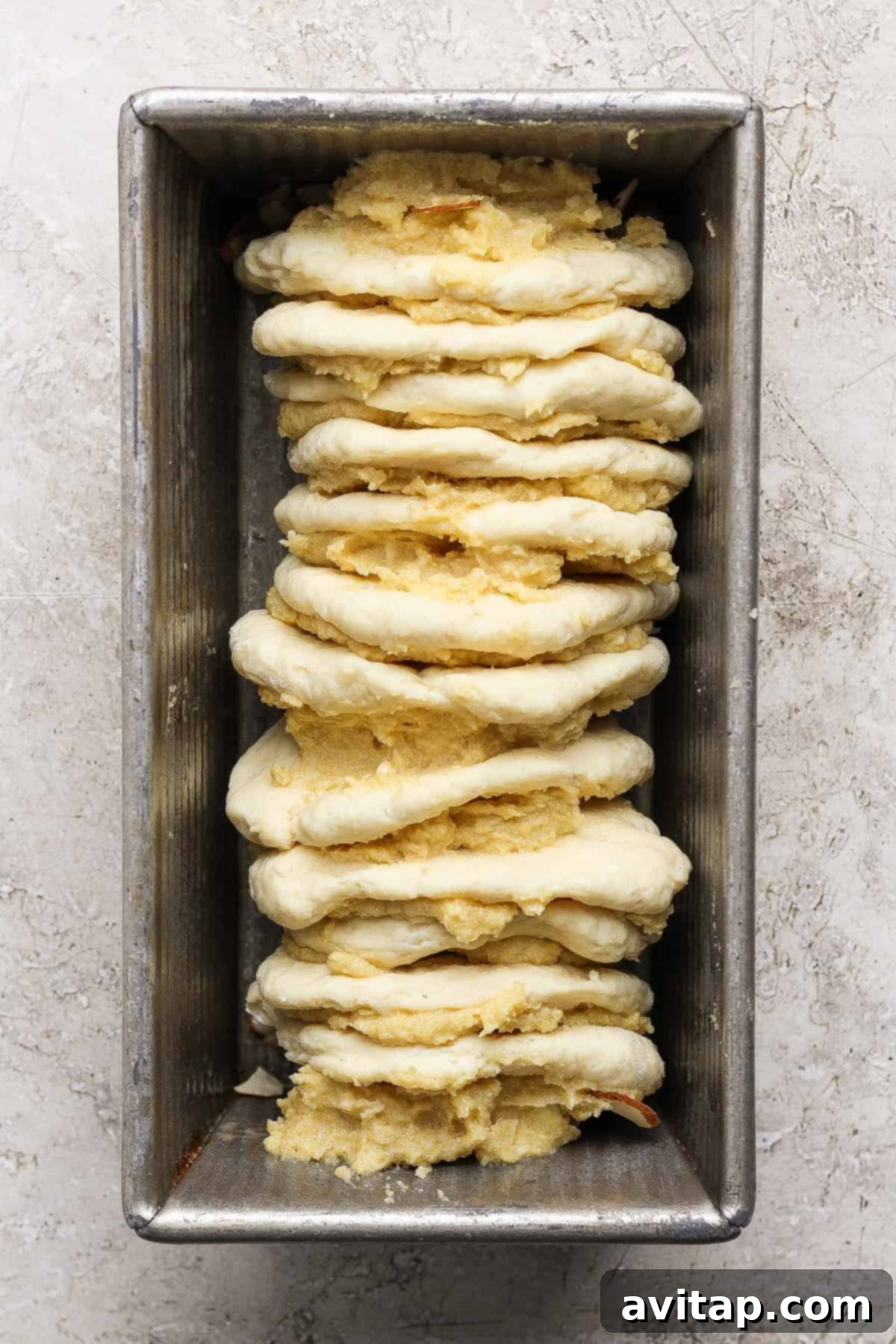 Unbaked pull-apart bread in a loaf pan, showcasing the layered dough and frangipane filling, ready to be baked to perfection.