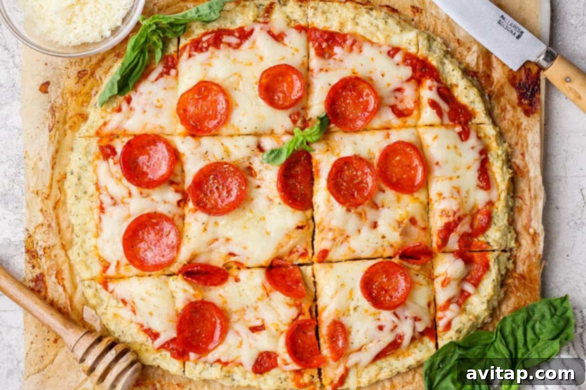 A delicious chicken crust pizza topped with melted cheese and pepperoni, cut into square slices and garnished with fresh basil.