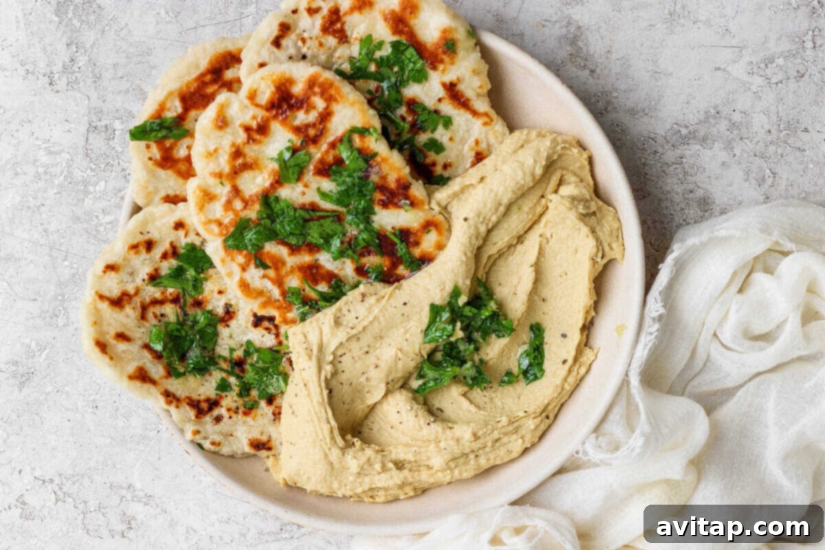 Grilled garlic naan flatbreads with herbs and hummus