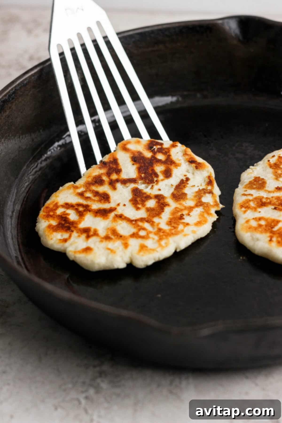 Flipping garlic naan in a skillet