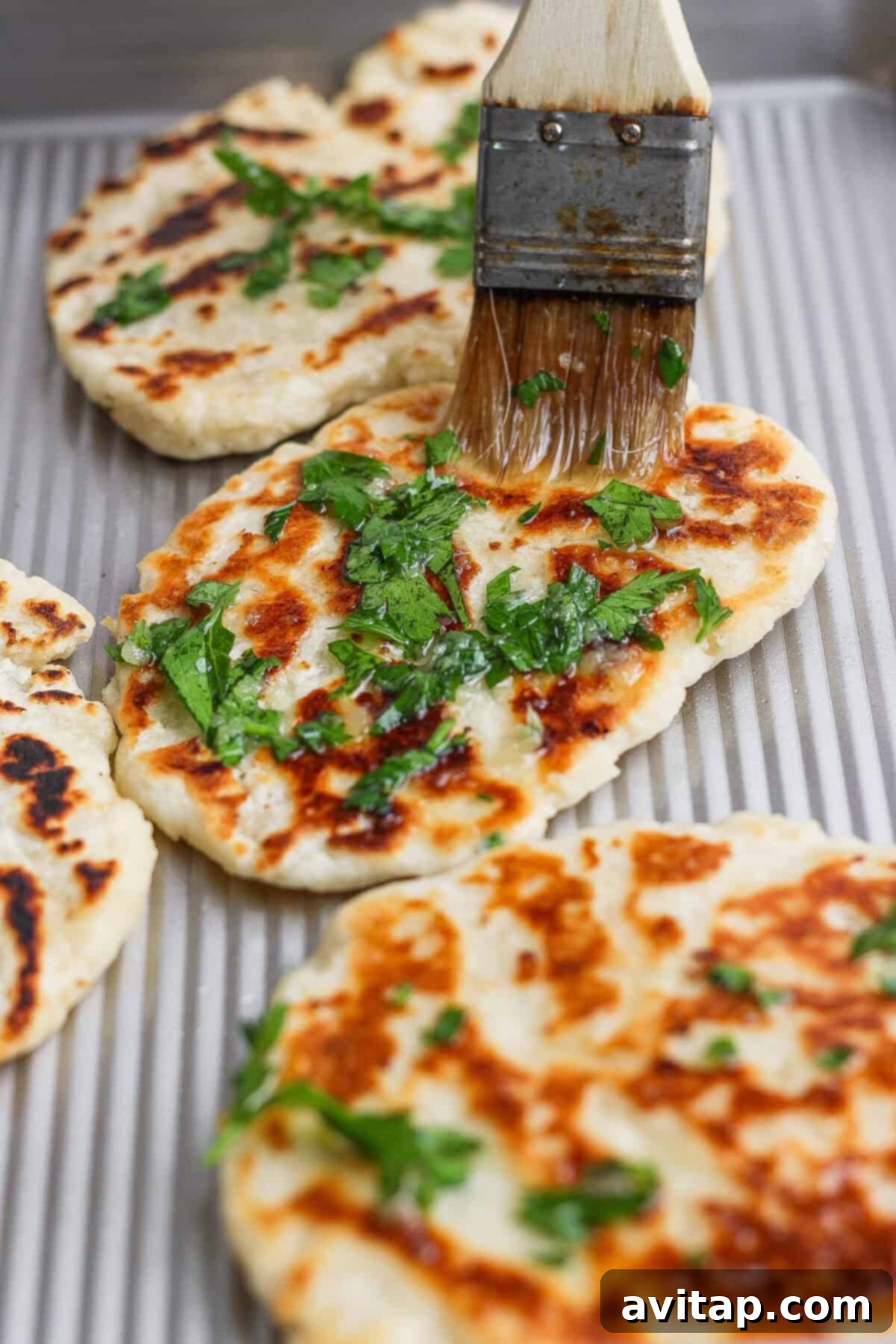 Brushing garlic naan with olive oil and herbs