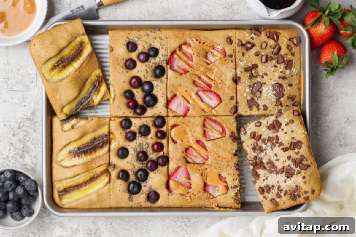 Sheet pan protein pancakes with various toppings: banana, blueberries, strawberries, peanut butter, and chocolate chips.