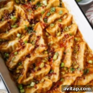 High-Protein Trader Joe's Meal Ideas 10 A white baking dish filled with cooked dumplings in a spicy sauce, garnished with chopped green onions, cilantro, and sesame seeds. A plate of lime wedges is nearby.