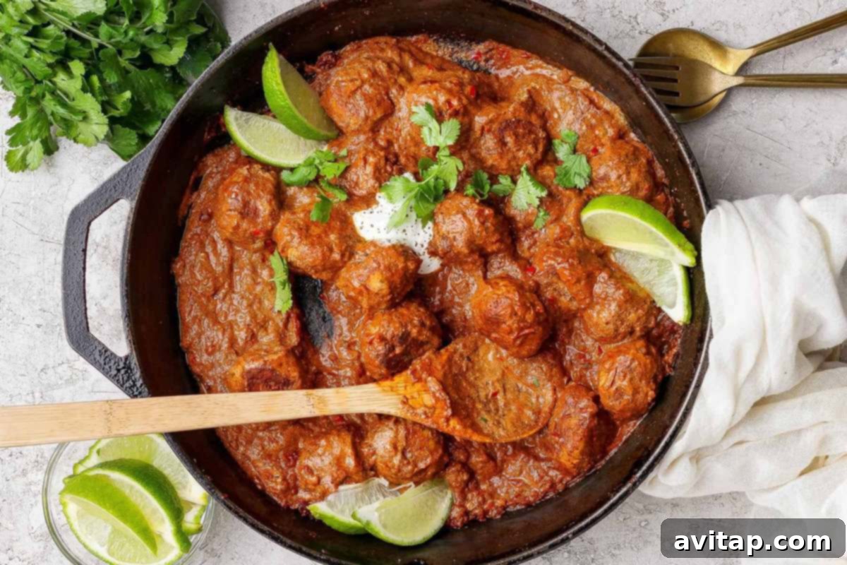 Butter chicken meatballs in a cast iron skillet with lime and cilantro