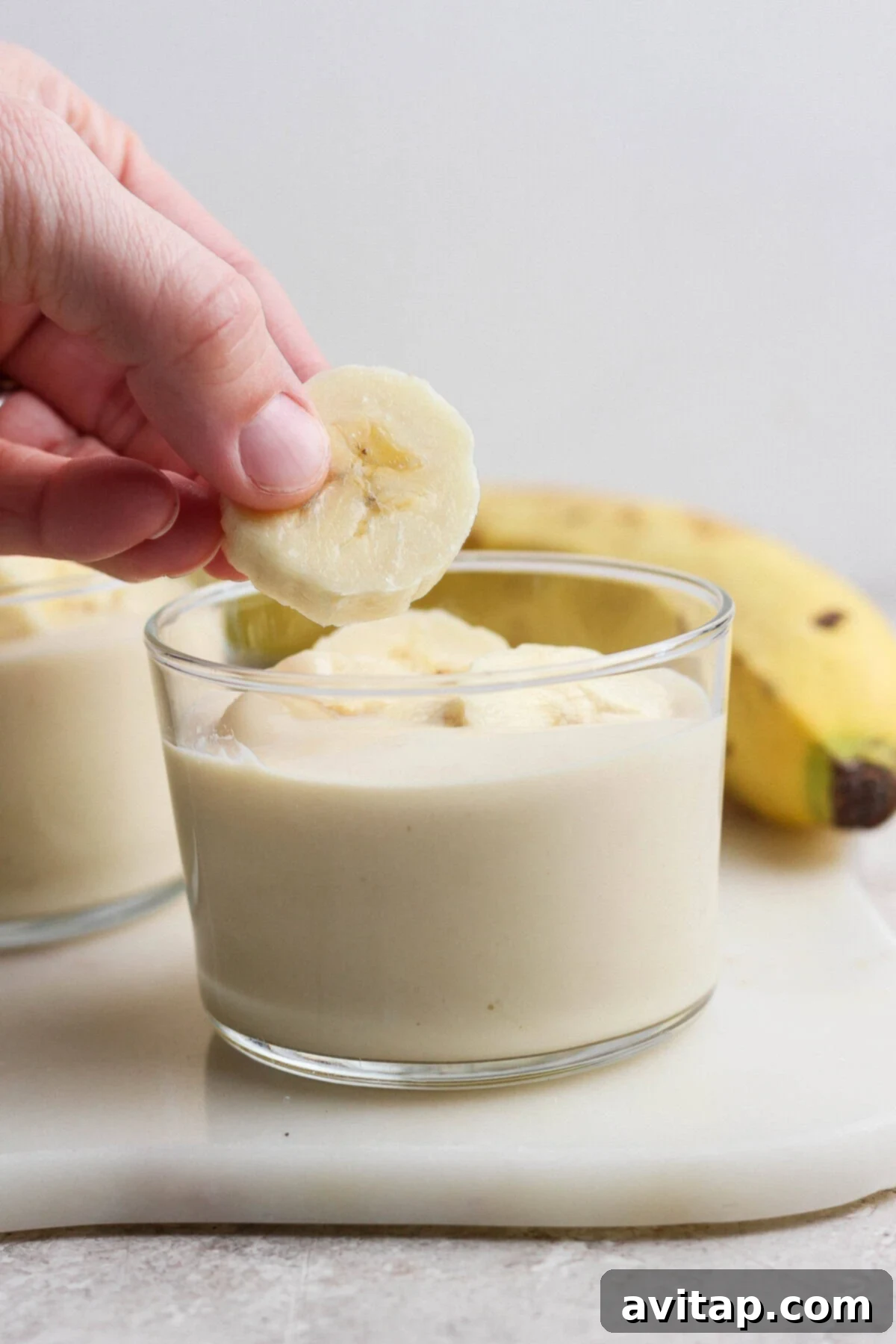 High-Protein Banana Bliss 5 Adding fresh banana slices to a cup of banana pudding
