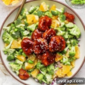 A close up picture of glazed chicken with broccoli, oranges, and edamame.
