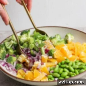 A person mixing salad with salad utensils.