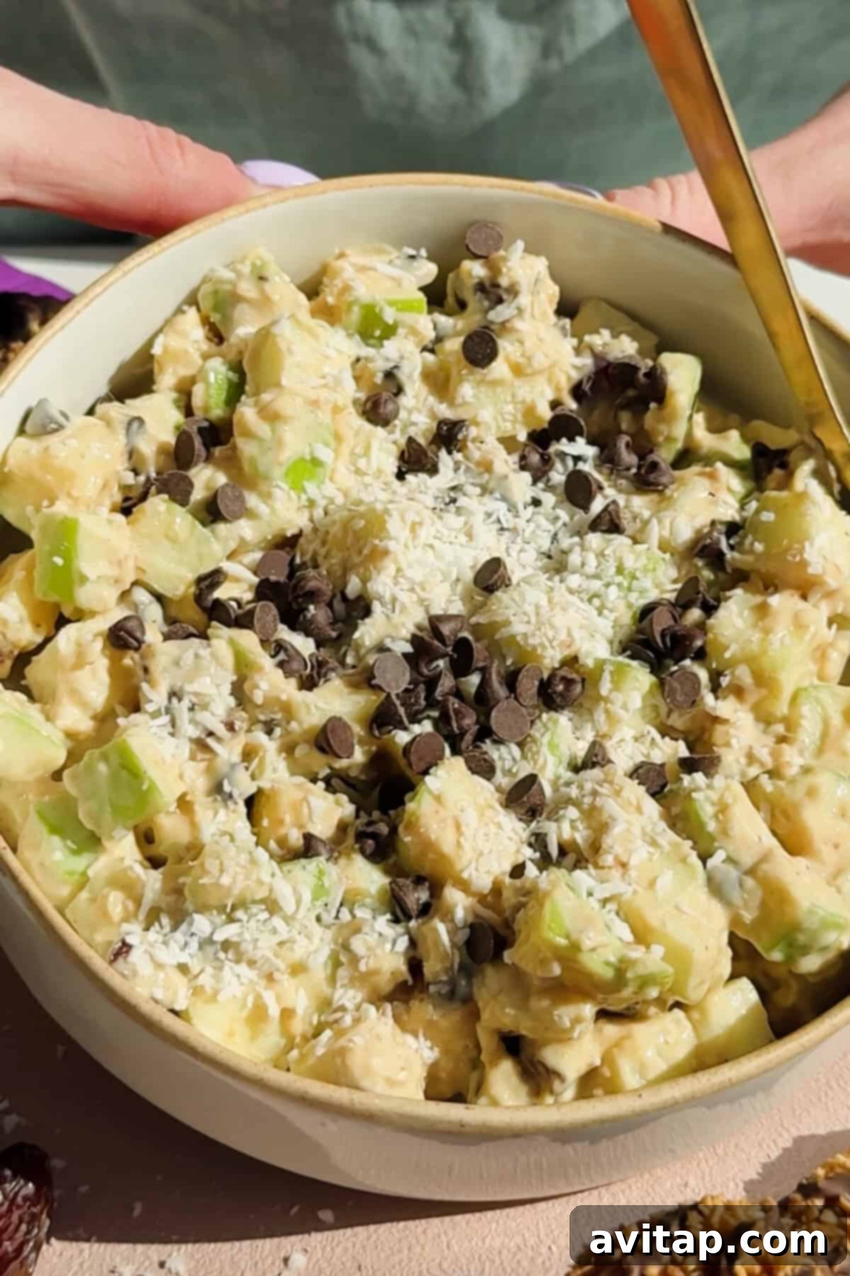 A delicious bowl of Caramel deLites Apple Salad topped with shredded coconut and chocolate chips.
