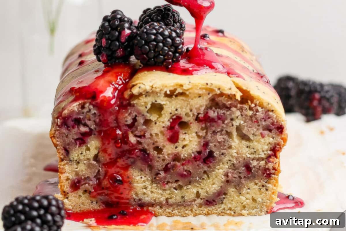 A perfectly baked blackberry lemon poppy seed loaf topped with fresh blackberries and a drizzle of sweet blackberry glaze.