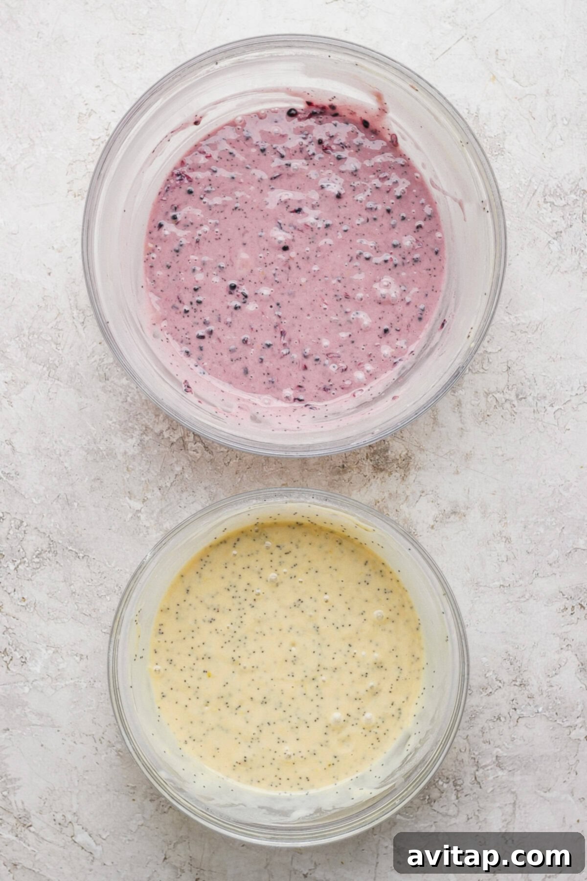 Two bowls of batter: one with blackberries and one with poppy seeds