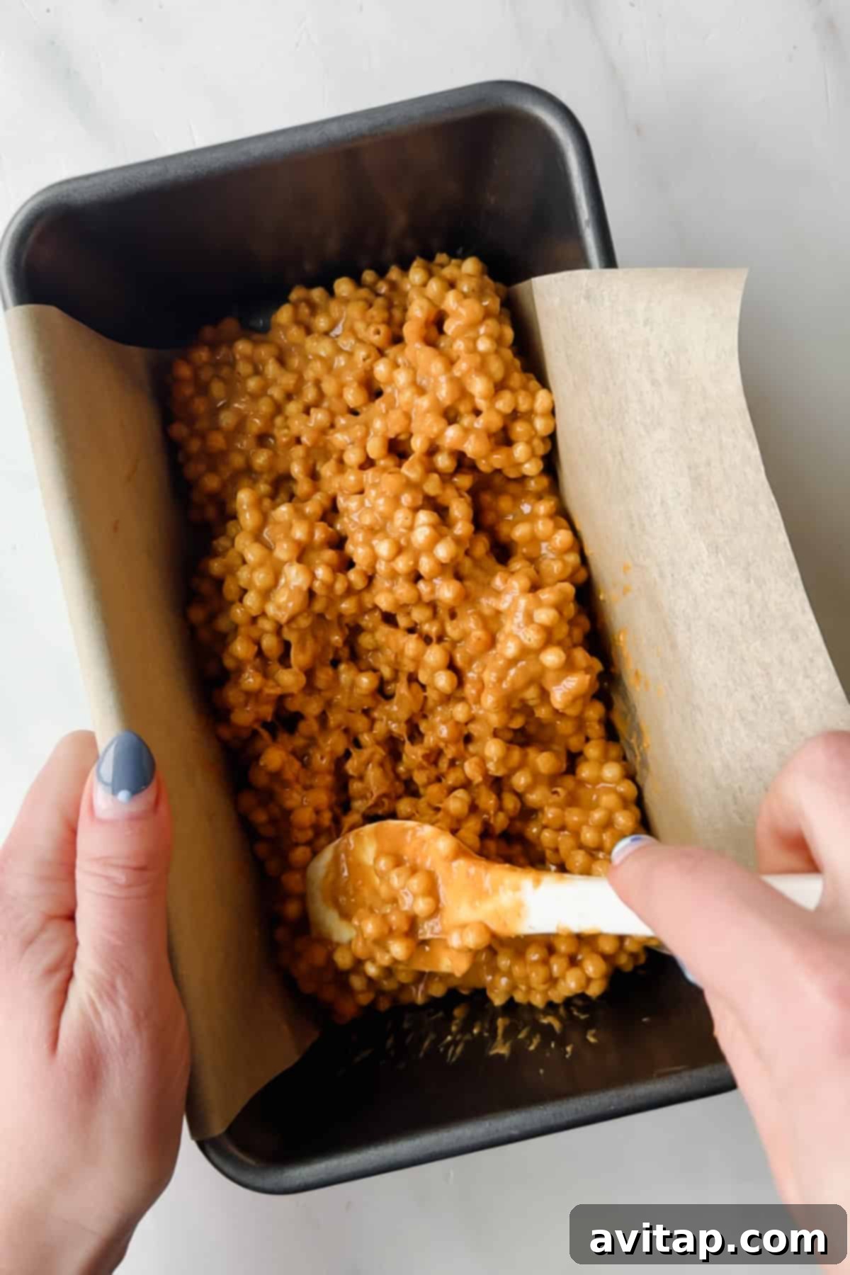 Spreading the peanut butter mixture into a parchment-lined pan.