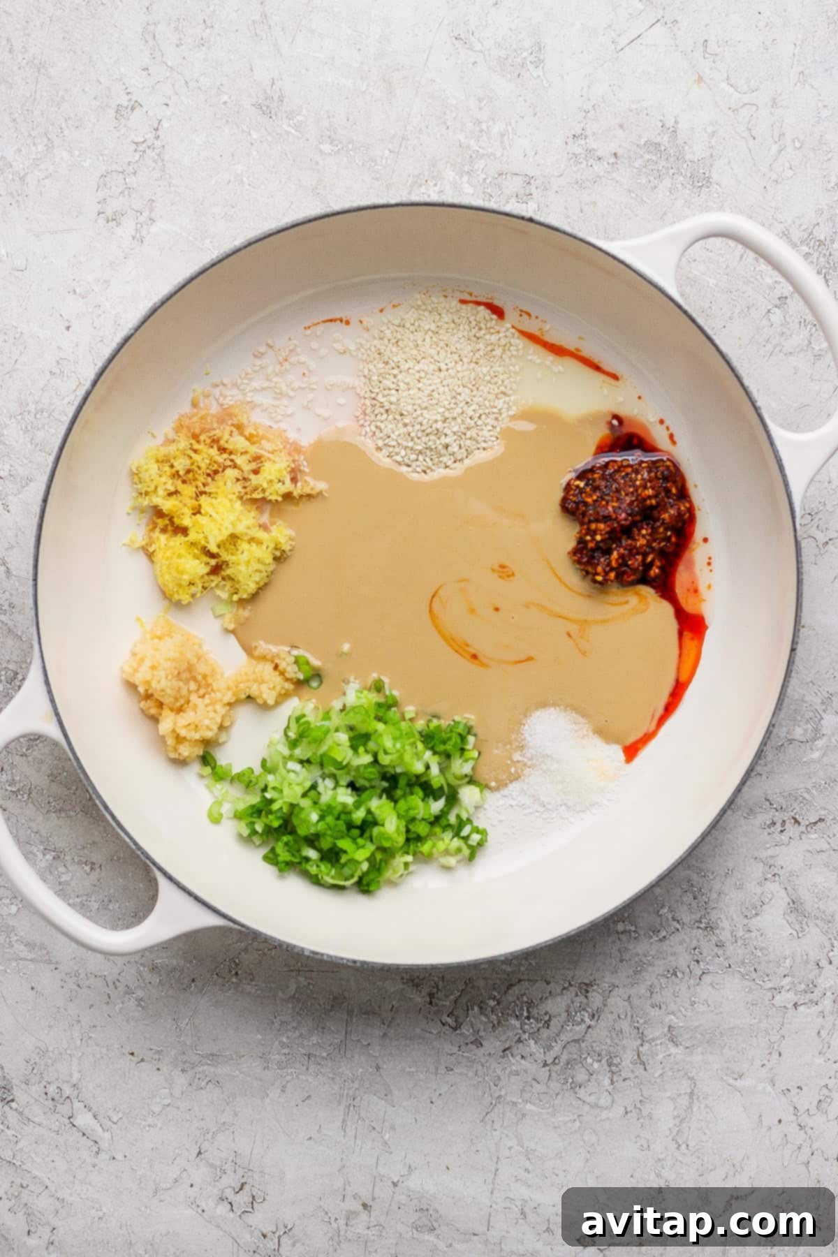 Ingredients for Tahini Chili Oil Noodles, including tahini, chili crunch, sesame seeds, garlic, and green onions.