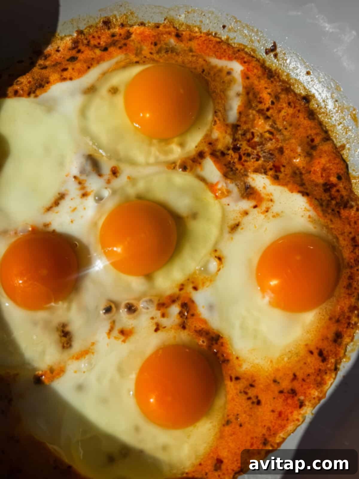 Close-up of heavy cream fried eggs cooking in a pan.
