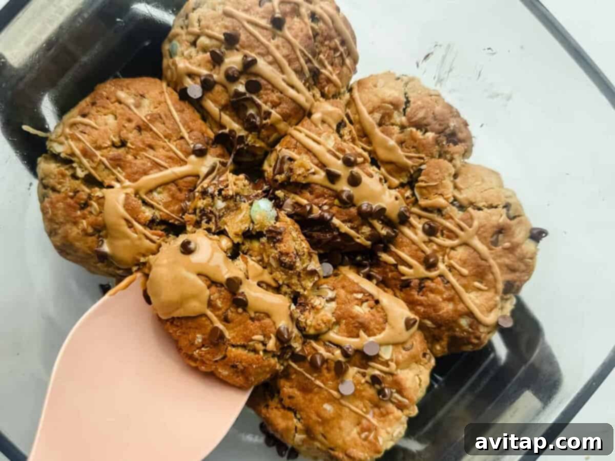 A glass dish containing chunky scoopable cookies drizzled with icing and mini chocolate chips.