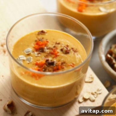 A visually appealing bowl of creamy carrot cake smoothie, garnished with a sprinkle of oats, presented on a rustic wooden cutting board, signifying a healthy and delicious start to the day.