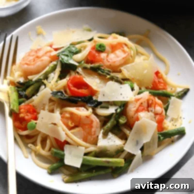 Shrimp scampi with asparagus served over a plate of pasta.