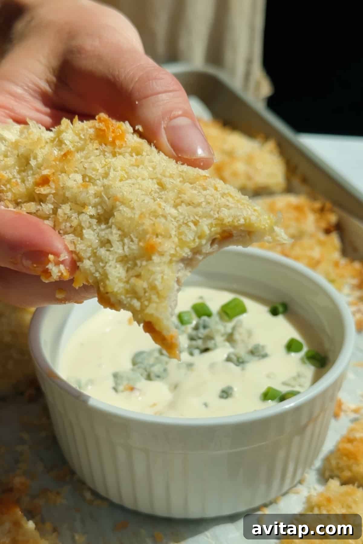 Buffalo Chicken Protein Bars — Crispy Baked Snackable Bars 8 Dipping a crispy chicken protein bar into blue cheese dressing topped with crumbled cheese and green onions