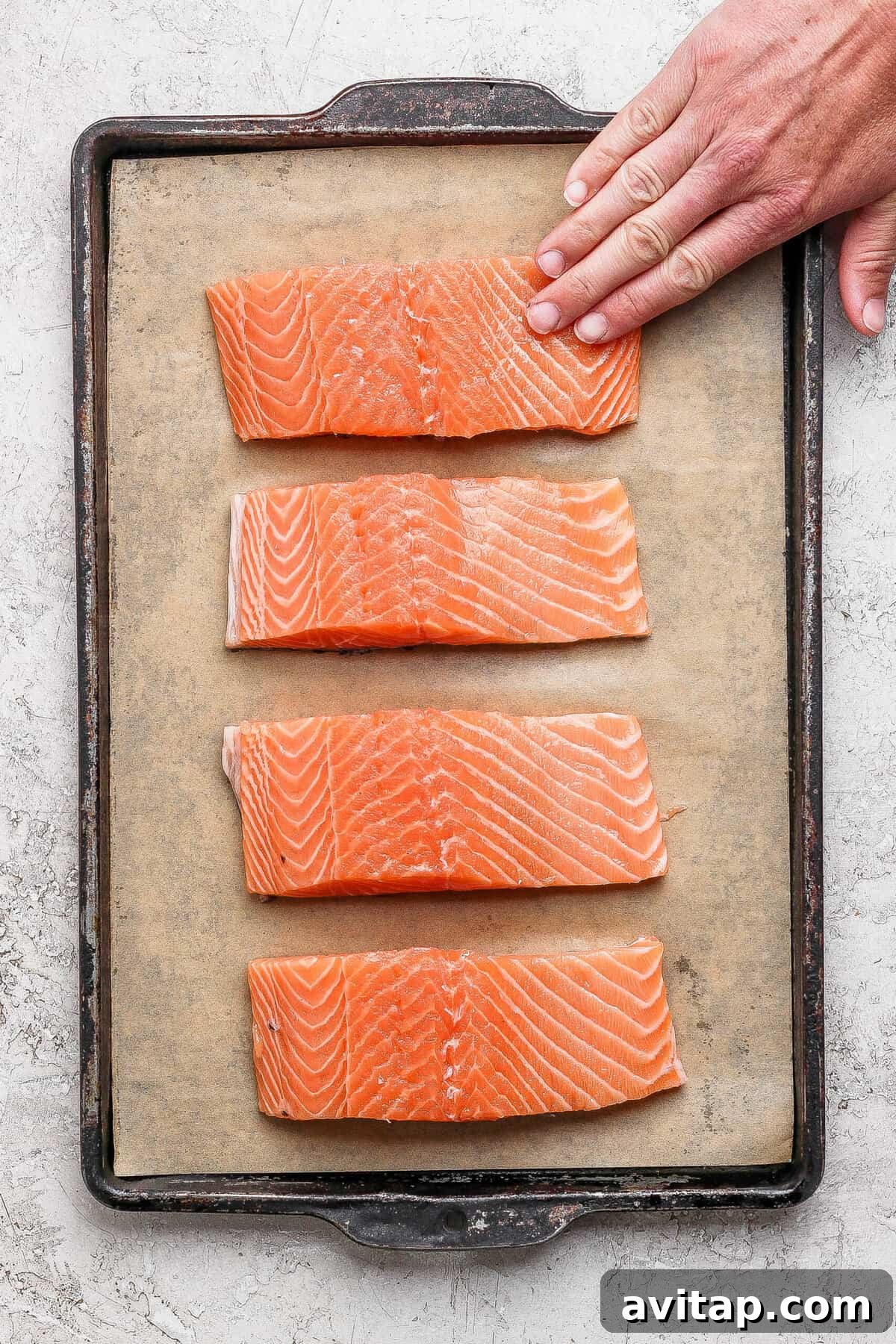 Seasoned salmon fillets arranged on a parchment-lined baking sheet ready for the broiler.