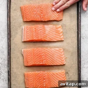 Seasoned salmon fillets arranged on a parchment-lined baking sheet ready to broil.