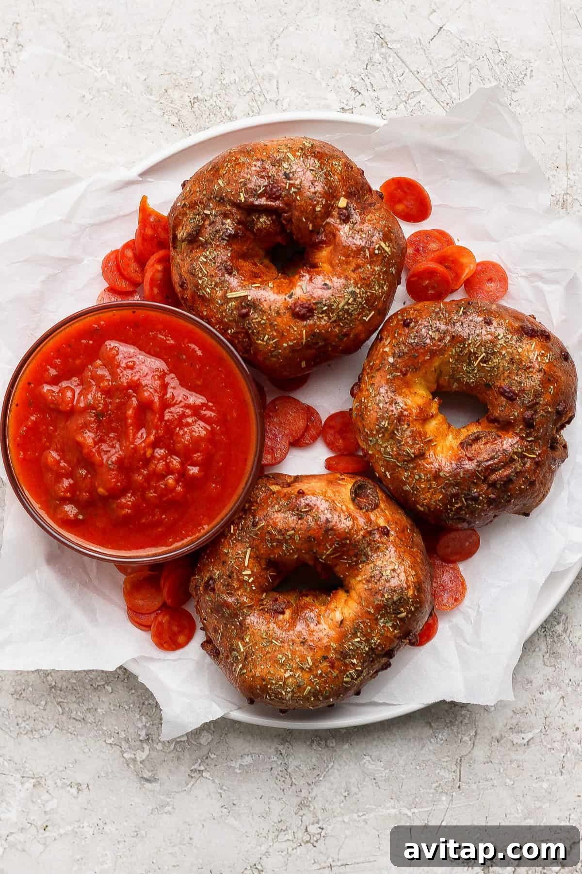 Overhead view of three baked pizza protein bagels with marinara sauce and pepperoni