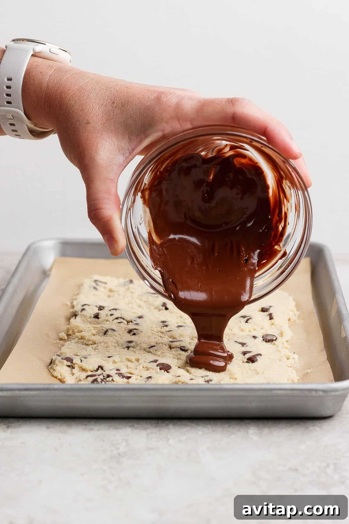 pouring melted chocolate over frozen cottage cheese cookie dough bark