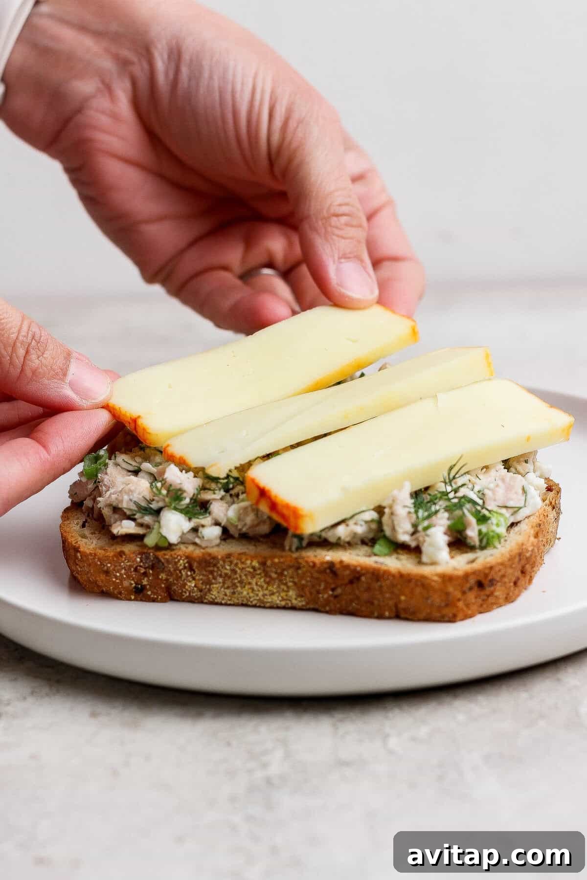 placing muenster cheese slices on tuna melt