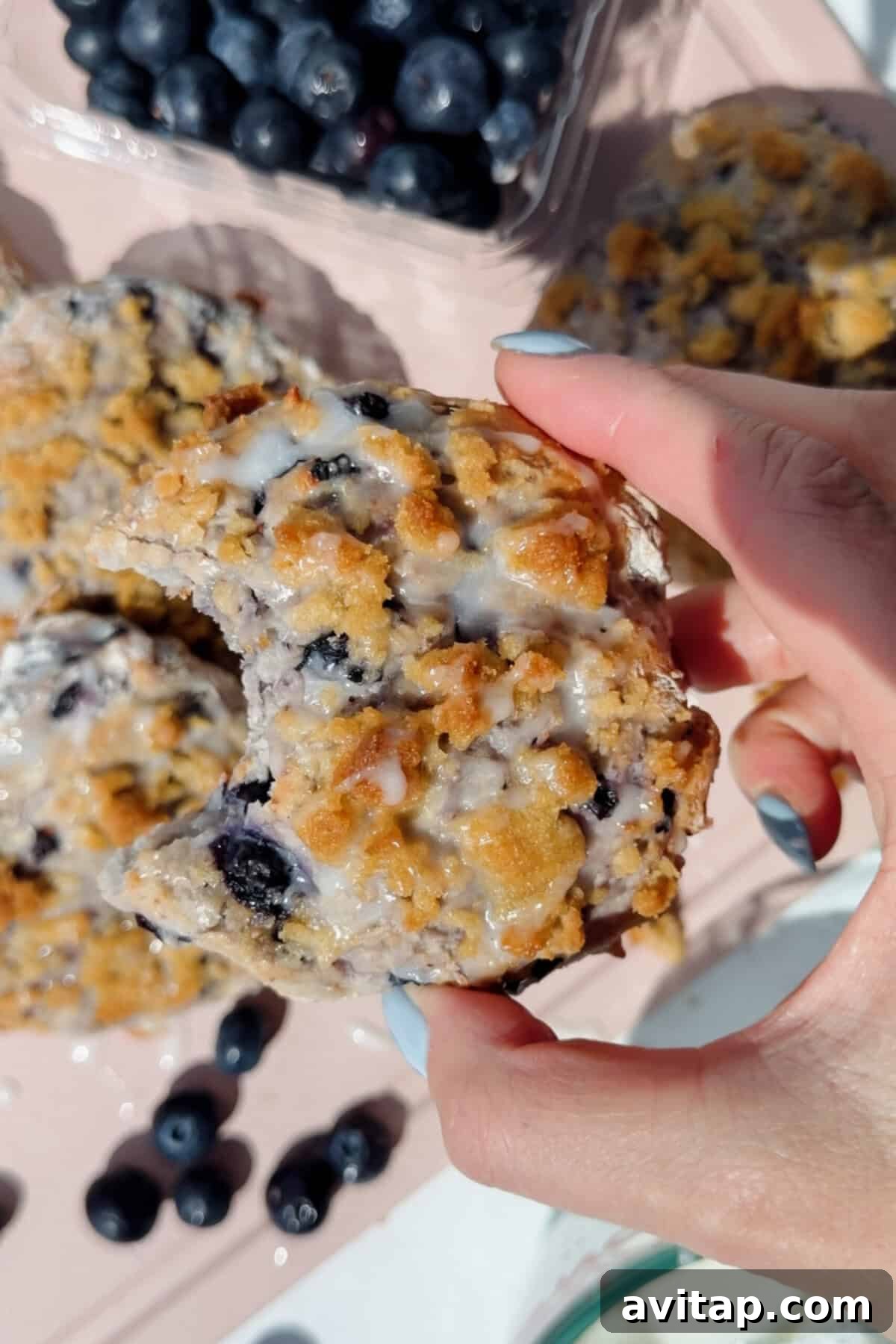 hand holding a blueberry cottage cheese biscuit with a bite taken out showing fluffy interior