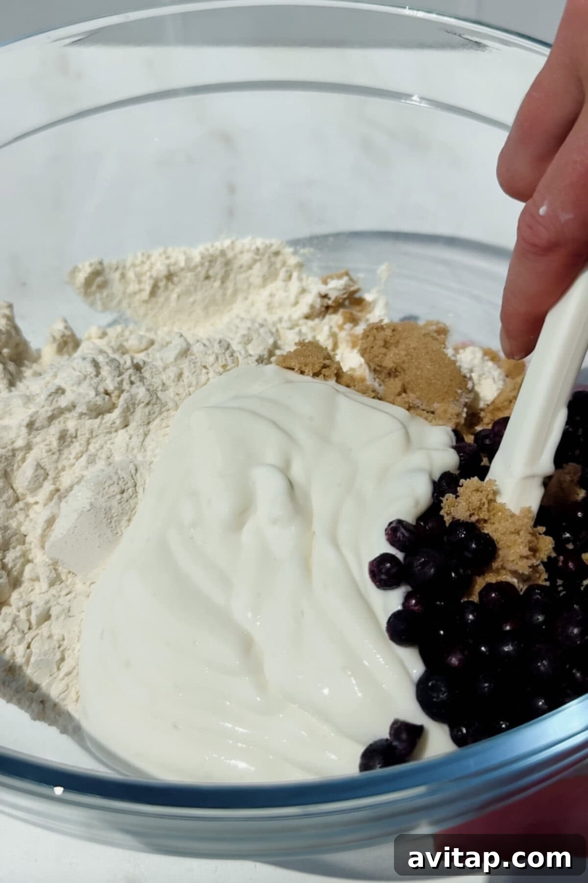 mixing flour cottage cheese blueberries and brown sugar in a bowl for blueberry biscuits