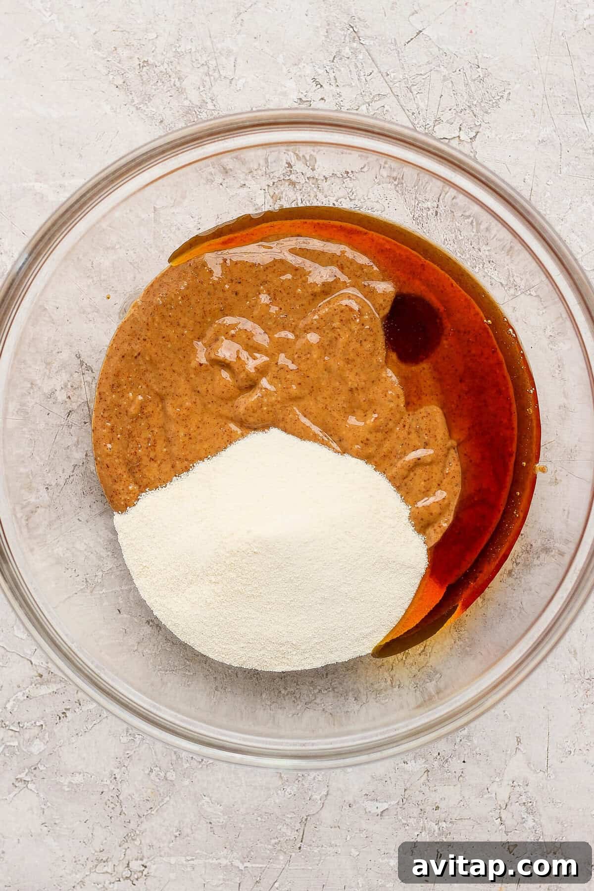 mixing almond butter maple syrup and protein powder in a glass bowl for thin mint protein bites