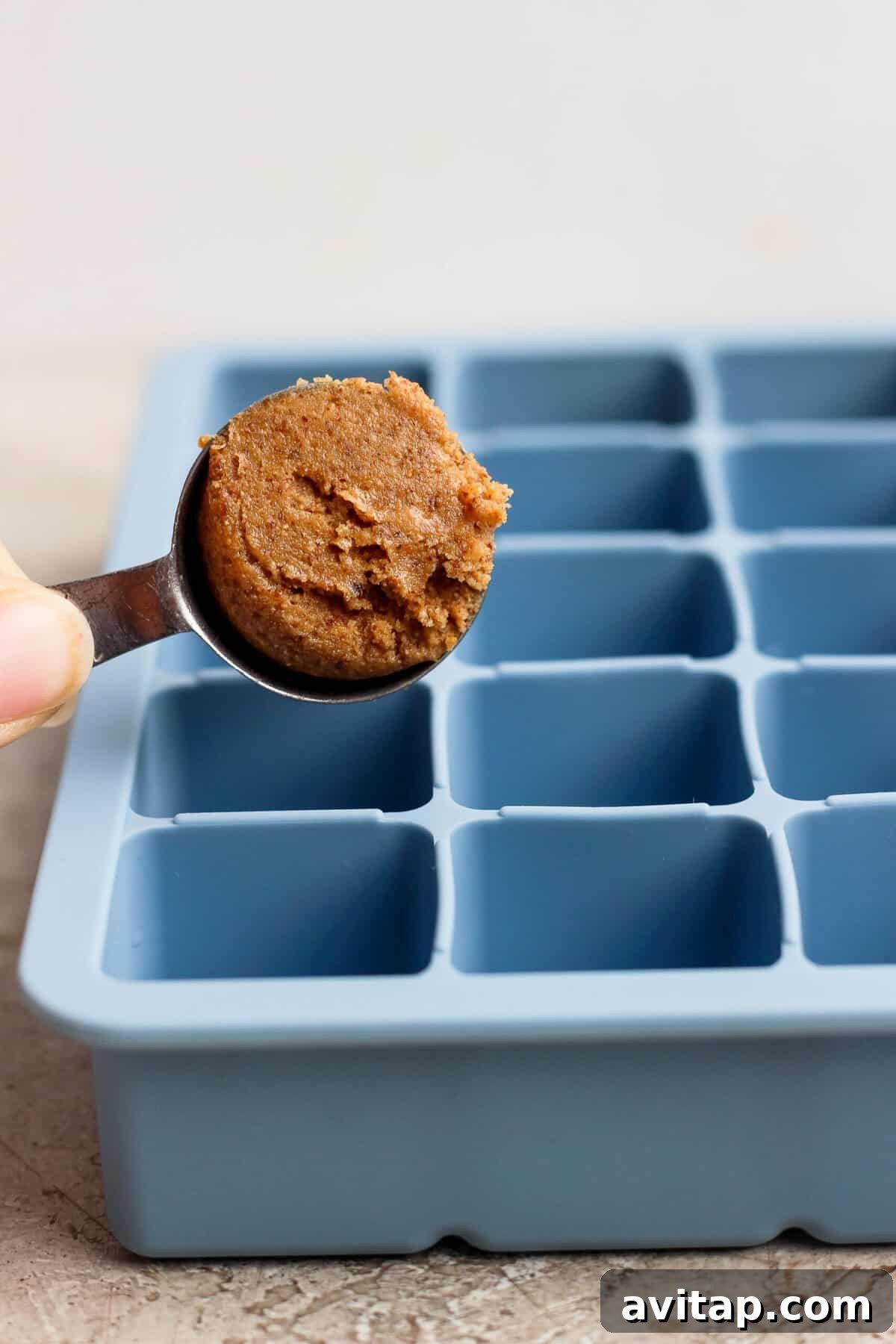 spooning protein bite mixture into a blue silicone ice cube tray