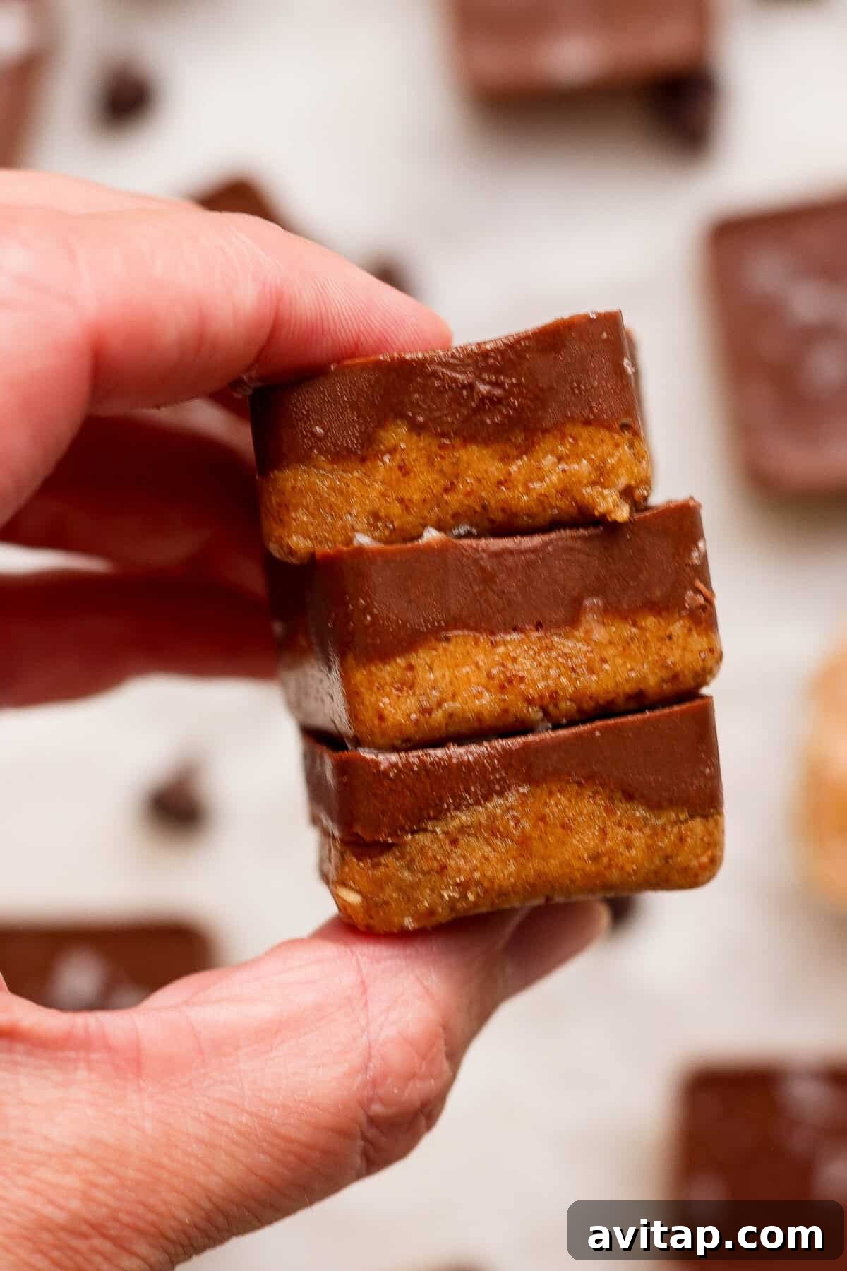 hand holding a stack of three no bake thin mint protein bites with chocolate coating
