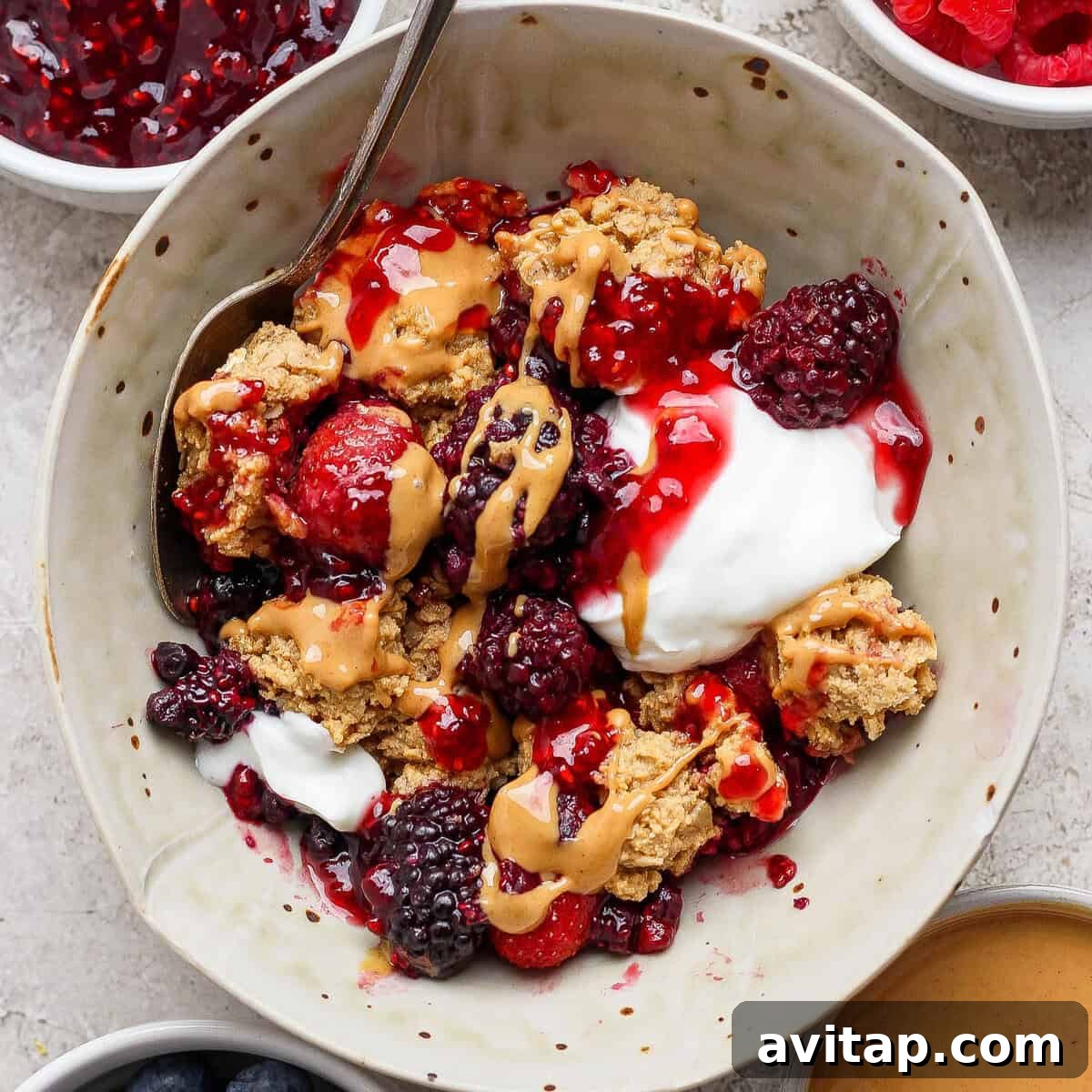 protein berry crumble served in a bowl with yogurt and peanut butter drizzle