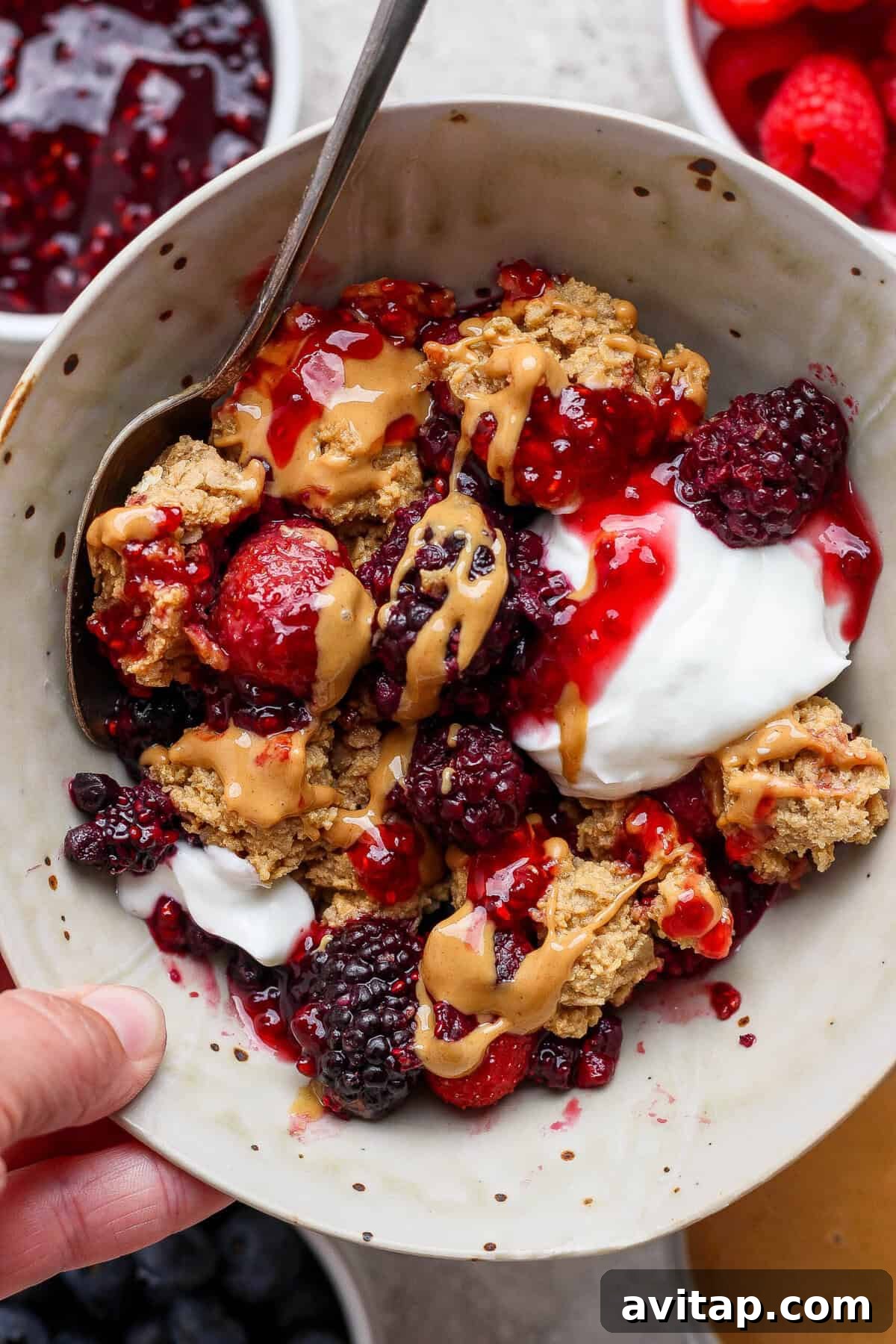 bowl of protein berry crumble with yogurt blackberries strawberries and peanut butter drizzle