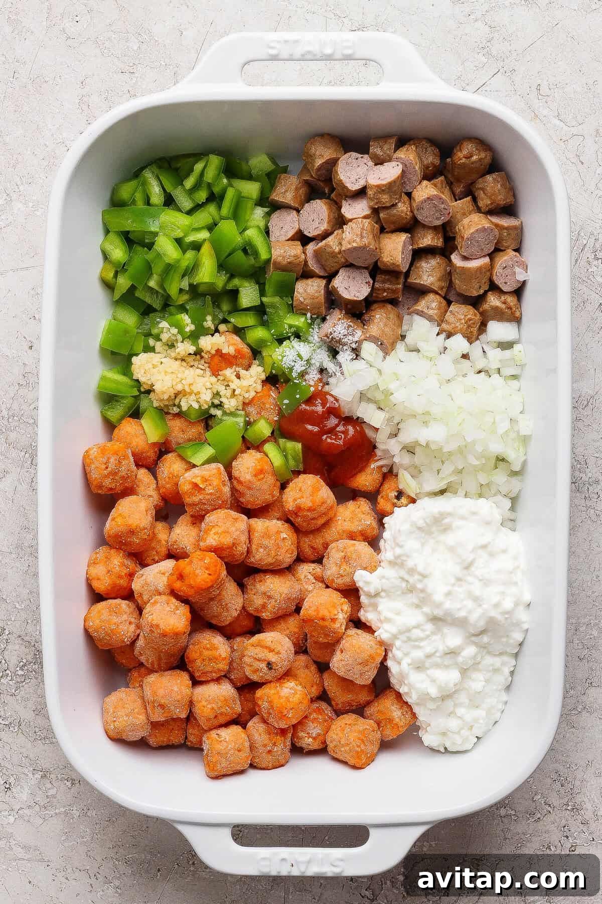 sweet potato tater tots sausage and vegetables in baking dish before adding eggs