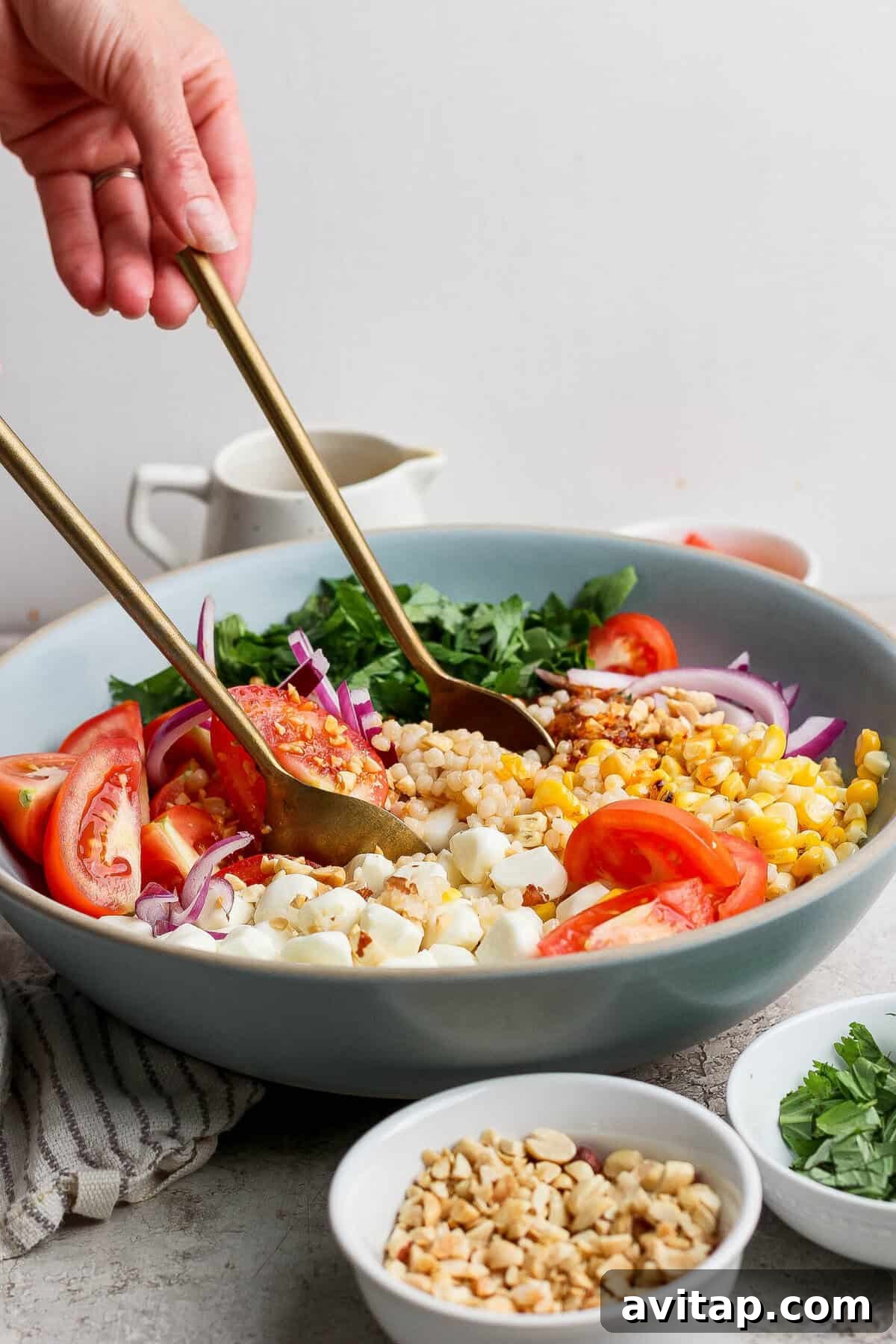 tossing corn tomato salad with chili crunch dressing in a large bowl