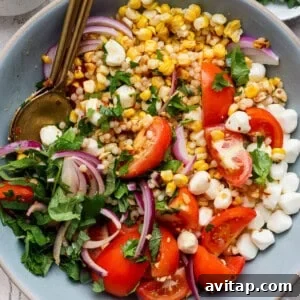 corn tomato salad with mozzarella pearls chili crunch dressing and fresh cilantro in a bowl