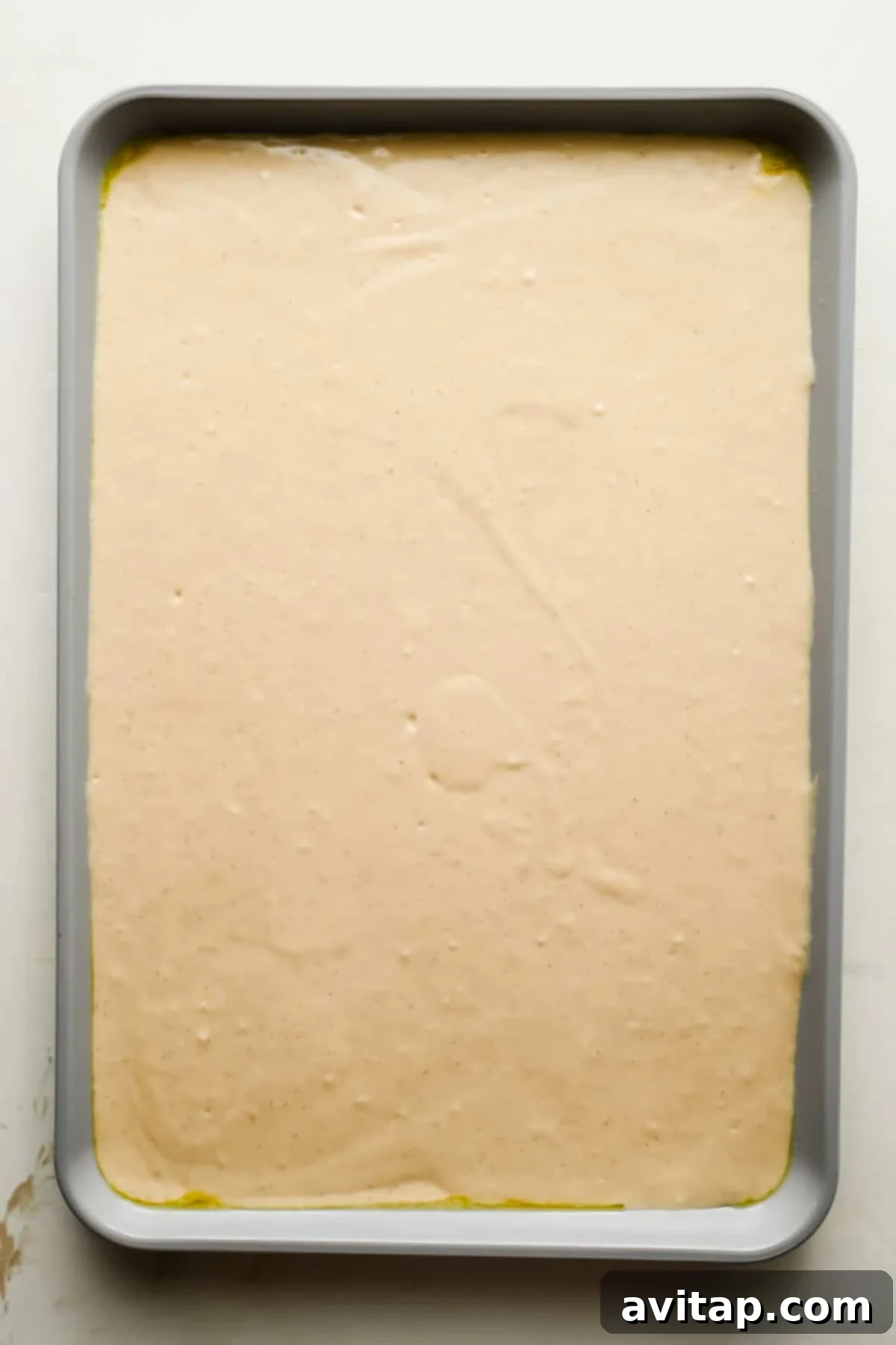Pancake batter spread evenly in a greased quarter sheet pan.