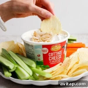 A ridged potato chip dipped into creamy cottage cheese French onion dip served with chips, carrots, and celery.